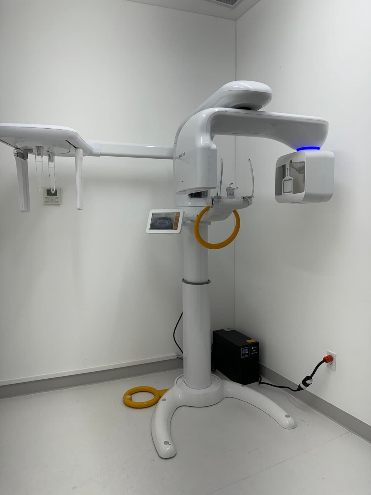 Un equipo de rayos X dental panorámico en una sala de imagenología blanca y vacía